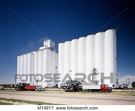 1970s white grain elevators trucks parked in front of silos against blue sky View Large Photo Image Stock Photo - 1970s white grain elevators trucks parked in front of silos against blue sky. Fotosearch