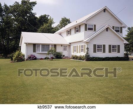 Stock Photo - 1970s white suburban house with olive shutters and double peaked roof. Fotosearch