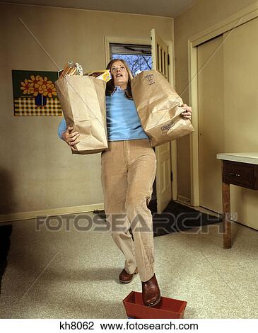 1970s woman holding grocery bags falling stepping on a toy View Large Photo Image Stock Image - 1970s woman holding grocery bags falling stepping on a toy. Fotosearch