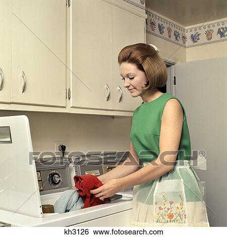 1970s woman housewife homemaker wearing apron loading laundry into washing machine View Large Photo Image Stock Photograph - 1970s woman housewife homemaker wearing apron loading laundry into washing machine. Fotosearch