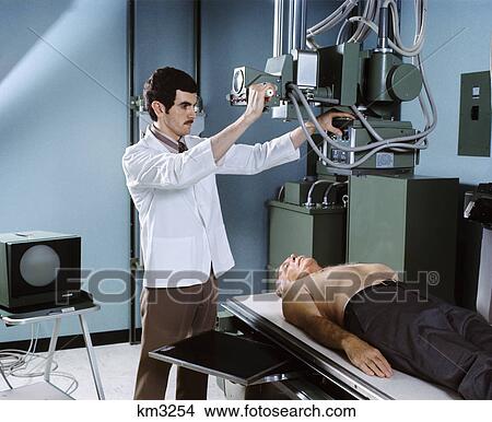Picture - 1970s x-ray technician middle aged man patient. Fotosearch