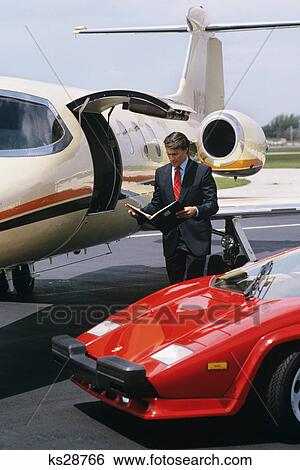 1980s 1990s business man standing between lamborghini and lear jet View Large Photo Image Stock Photograph - 1980s 1990s business man standing between lamborghini and lear jet. Fotosearch