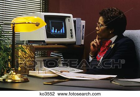 1980s african american woman executive at desk studying bar graph on pc display screen View Large Photo Image Stock Image - 1980s african american woman executive at desk studying bar graph on pc display screen. Fotosearch