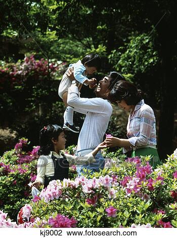 1980s asian family of four in woods picking flowers father lifting up child View Large Photo Image Stock Image - 1980s asian family of four in woods picking flowers father lifting up child. Fotosearch