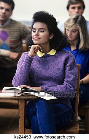 Stock Image - 1980s attentive female college student purple sweater in classroom. Fotosearch