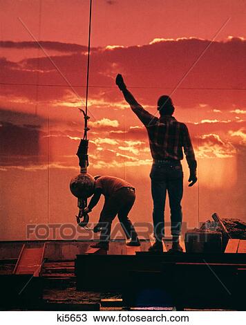 1980s construction worker giving hand signal a second man attaches crane hook to materials to be lifted View Large Photo Image Stock Image - 1980s construction worker giving hand signal a second man attaches crane hook to materials to be lifted. Fotosearch