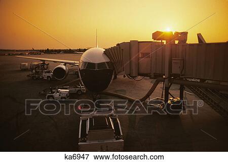 1980s front view of airplane boarding tunnel attached sun in background View Large Photo Image Stock Photo - 1980s front view of airplane boarding tunnel attached sun in background. Fotosearch