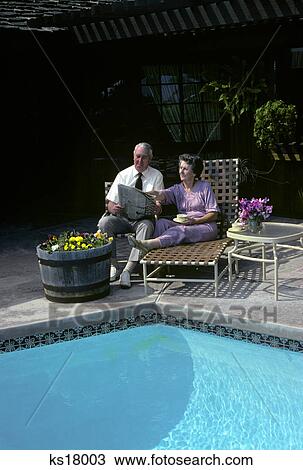 1980s senior couple reading newspaper by swimming pool View Large Photo Image Stock Image - 1980s senior couple reading newspaper by swimming pool. Fotosearch