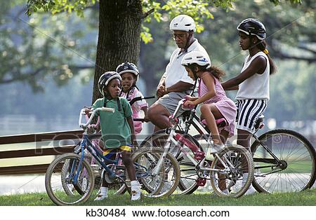 1990s african american family bicycling wearing helmets View Large Photo Image Picture - 1990s african american family bicycling wearing helmets. Fotosearch