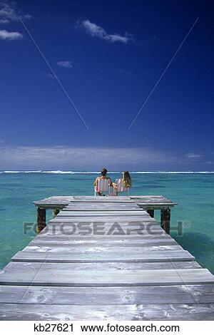 1990s couple sitting on a pier in an ocean lagoon in the tropics View Large Photo Image Stock Image - 1990s couple sitting on a pier in an ocean lagoon in the tropics. Fotosearch