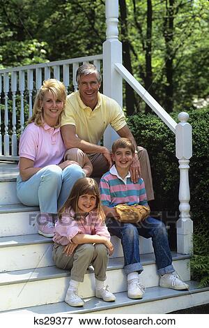 Stock Photo - 1990s parents with two children sitting on porch steps. Fotosearch