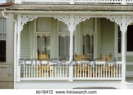 Stock Image - cape may new jersey white painted wood porch with wicker rocking chairs summer nostalgia seashore victorian vacation. Fotosearch