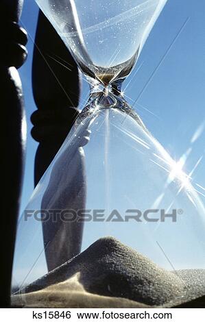Stock Photograph - close-up sand falling through hourglass. Fotosearch