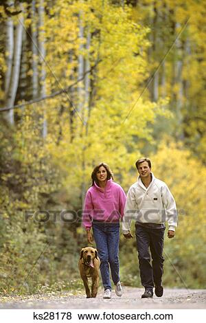 couple man woman walking down autumn country lane with dog View Large Photo Image Stock Photo - couple man woman walking down autumn country lane with dog. Fotosearch