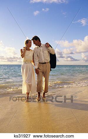 couple on the beach walking by the water dressed up View Large Photo Image Stock Photo - couple on the beach walking by the water dressed up. Fotosearch