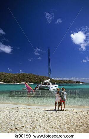 couple standing on beach watching a sailboarder and a catamaran tobago cays, west indies View Large Photo Image Stock Image - couple standing on beach watching a sailboarder and a catamaran tobago cays, west indies. Fotosearch