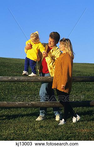 daughter walking on wooden fence supported by mother and father View Large Photo Image Stock Image - daughter walking on wooden fence supported by mother and father. Fotosearch