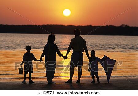 family at the beach at sunset holding a kite View Large Photo Image Stock Image - family at the beach at sunset holding a kite. Fotosearch