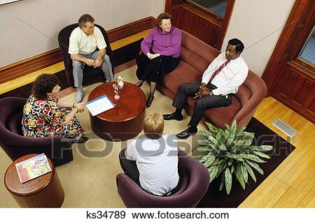Stock Photo - five adults sitting in circle therapy session. Fotosearch