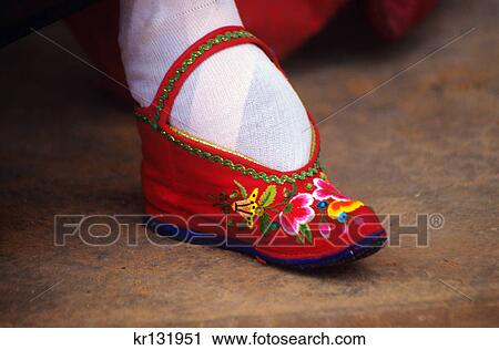 Stock Image - foot of chinese woman bound into tiny red embroidered shoe yunnan province china. Fotosearch