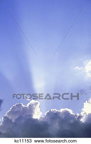 Stock Image - god like sun rays at top of cloud formation blue sky. Fotosearch