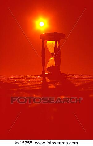 Stock Photography - hourglass silhouetted in red yellow sunburst. Fotosearch