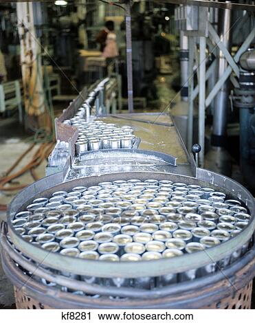 Stock Image - interior of tin cans in a food processing plant moving along conveyor belt. Fotosearch