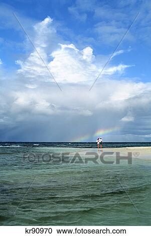 man and woman standing off in the distance, admiring a rainbow mopion island, grenadines, west indies View Large Photo Image Stock Image - man and woman standing off in the distance, admiring a rainbow mopion island, grenadines, west indies. Fotosearch