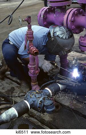 Stock Image - man welding industrial pipes. Fotosearch