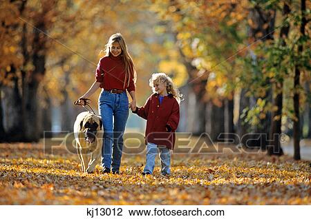 Stock Image - mother and child walking dog in autumn. Fotosearch