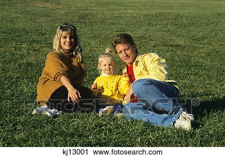 mother and father reclining on grassy hill with daughter between them View Large Photo Image Stock Image - mother and father reclining on grassy hill with daughter between them. Fotosearch