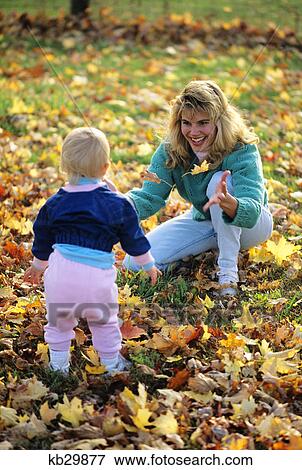 mother and small child playing in fall leaves View Large Photo Image Stock Photo - mother and small child playing in fall leaves. Fotosearch