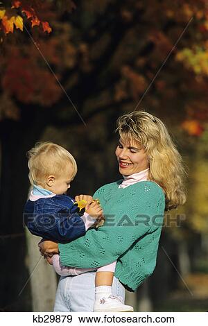 Stock Photo - mother and small child with fall leaves in background. Fotosearch