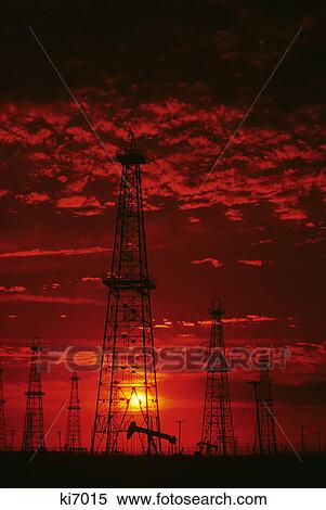 red sky sunset over oil field silhouetted derricks and pumps View Large Photo Image Stock Photography - red sky sunset over oil field silhouetted derricks and pumps. Fotosearch