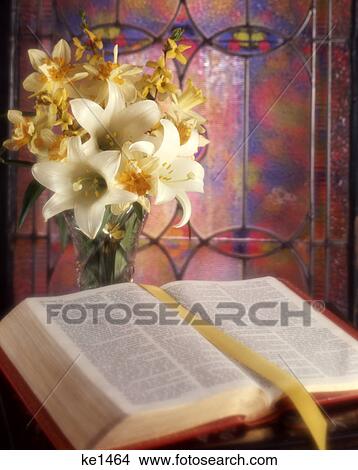 Picture - spring bouquet of lilies and daffodils with an open bible by stained glass window. Fotosearch