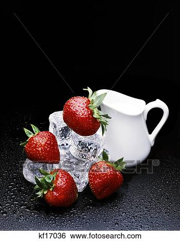 Stock Photograph - strawberries on ice with cream pitcher black background. Fotosearch