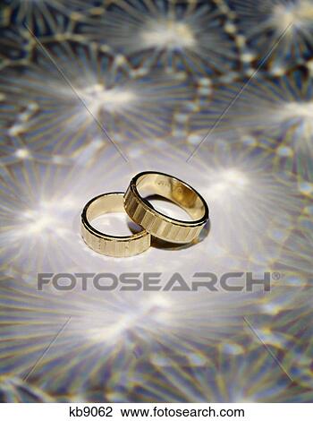 two gold wedding ring bands on a patterned background View Large Photo Image Stock Image - two gold wedding ring bands on a patterned background. Fotosearch