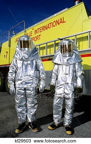 Stock Image - two people in silver fire fighting suits. Fotosearch