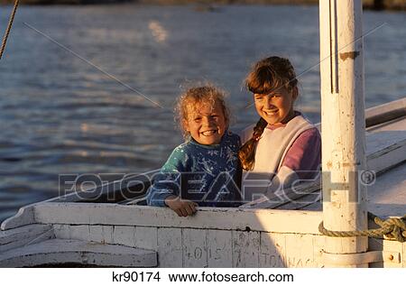 Picture - two smiling girls aboard fishing boat county donegal, ireland. Fotosearch