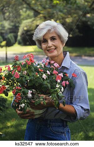 woman holding flowering plant View Large Photo Image Stock Photo - woman holding flowering plant. Fotosearch