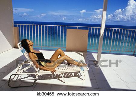 woman wearing black and gold bathing suit sitting in beach chair on deck View Large Photo Image Stock Photography - woman wearing black and gold bathing suit sitting in beach chair on deck. Fotosearch
