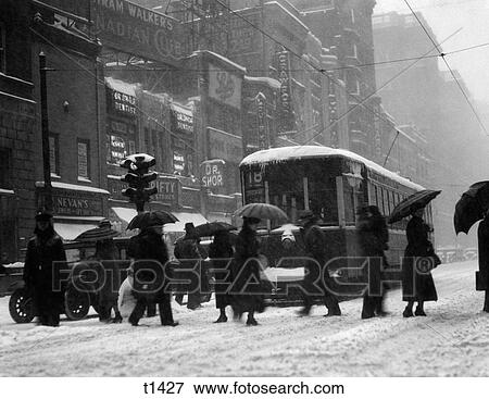 1920S 1930S Crowd Carrying Umbrellas Crossing Street In Front Of Street Car Trolley During Snowstorm View Large Photo Image Stock Photo - 1920S 1930S Crowd Carrying Umbrellas Crossing Street In Front Of Street Car Trolley During Snowstorm. Fotosearch