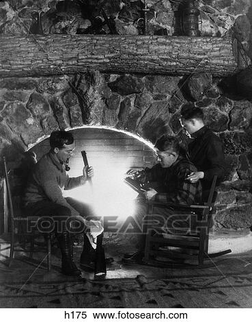 1920s 1930s Three Men Hunters Sitting By Stone Fireplace Cleaning