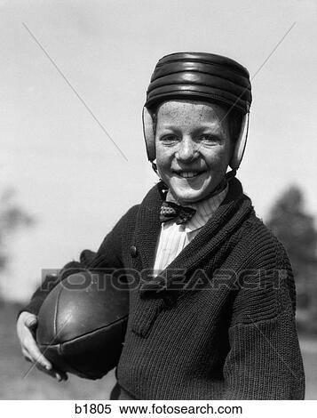 1920S Freckle-Faced Boy In Sweater & Bow Tie Wearing Leather Football Helmet Holding Football Under Arm View Large Photo Image Stock Photography - 1920S Freckle-Faced Boy In Sweater & Bow Tie Wearing Leather Football Helmet Holding Football Under Arm. Fotosearch