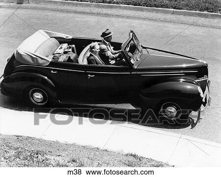 1930s 1940s Couple Husband And Wife Driving 1938 Convertible Four Door Sedan Automobile With Luggage In Back Seat Stock Photo