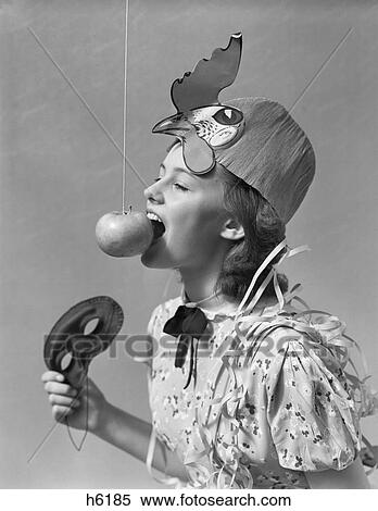 1930S 1940S Girl Bobbing For Apple Dangling On A String Wearing Party Hat And Holding Eye Mask View Large Photo Image Stock Photography - 1930S 1940S Girl Bobbing For Apple Dangling On A String Wearing Party Hat And Holding Eye Mask. Fotosearch