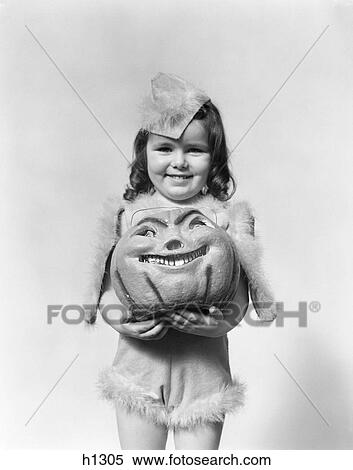 1930S 1940S Happy Smiling Little Girl In Costume Holding A Papier-Mache Pumpkin Head View Large Photo Image Stock Photography - 1930S 1940S Happy Smiling Little Girl In Costume Holding A Papier-Mache Pumpkin Head. Fotosearch