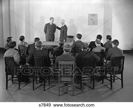 1930S 1940S Older Businessman Giving Younger Man Pat On The Back In Front Of Group Of Peers View Large Photo Image Stock Photo - 1930S 1940S Older Businessman Giving Younger Man Pat On The Back In Front Of Group Of Peers . Fotosearch
