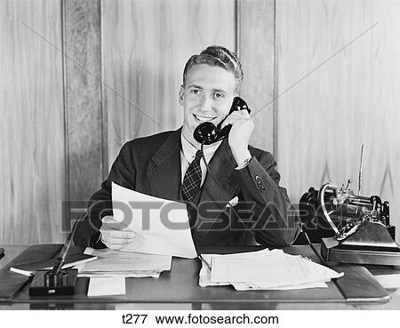 1930S 1940S Smiling Businessman Talking On Telephone Sitting At Desk With Dictation Machine View Large Photo Image Stock Photo - 1930S 1940S Smiling Businessman Talking On Telephone Sitting At Desk With Dictation Machine . Fotosearch