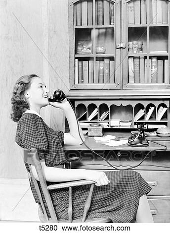 1930S 1940S Teenage Girl Sitting At Desk Talking On Old Black Rotary Dial Phone View Large Photo Image Stock Image - 1930S 1940S Teenage Girl Sitting At Desk Talking On Old Black Rotary Dial Phone . Fotosearch